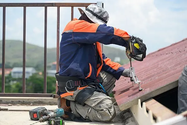 Roofer with a drill working on a tiled roof edge