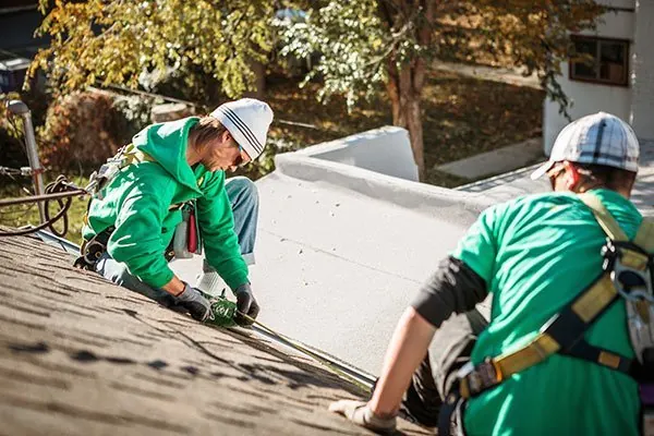 Two roofers in harnesses working on a pitched roof